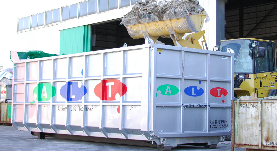 リサイクルボックスに重機を使って廃棄物を入れている画像